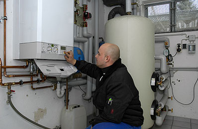 Ein Anlagenmechaniker kümmert sich um eine Wassererwärmungsanlage.