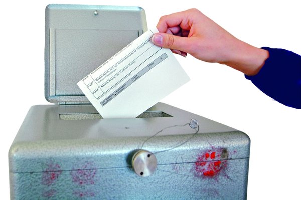 Zahlzettel wird in Wahlurne geworfen