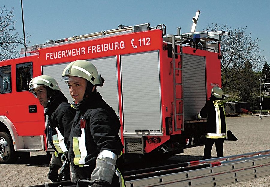 Zwei Feuerwehrmänner tragen eine Feuerleiter.