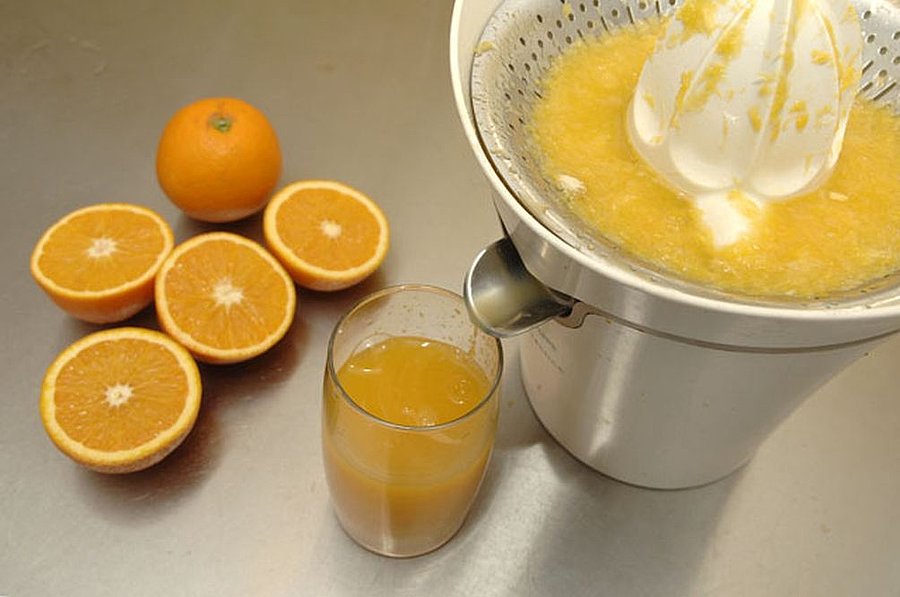 Mit einer Zitronen Presse werden Orangen zu Orangensaft gepresst.