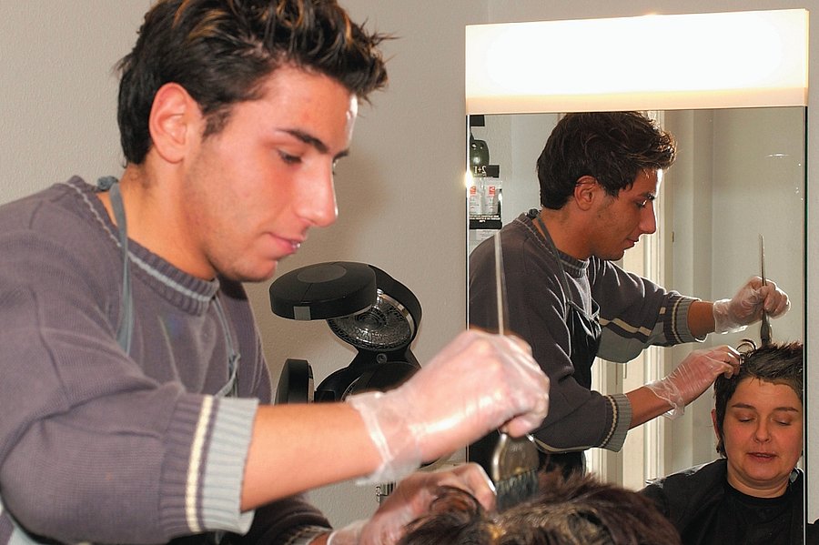 Ein Friseur schneidet einer Kundin die Haare.